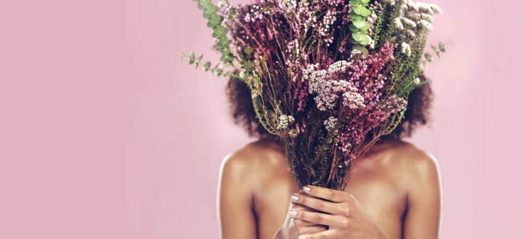 woman holding flowers in front of face and body