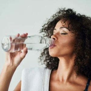 woman drinking from water bottle after workout